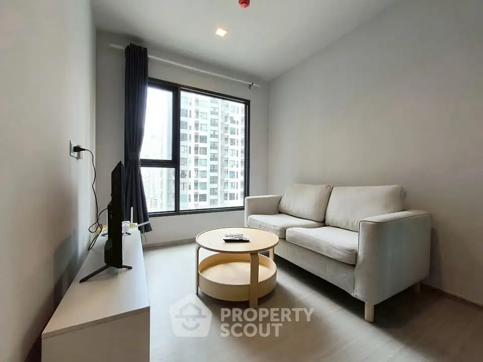 Modern living room with cozy sofa and large window offering city view.