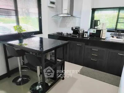 Modern kitchen with sleek black countertops and gas stove, perfect for culinary enthusiasts.