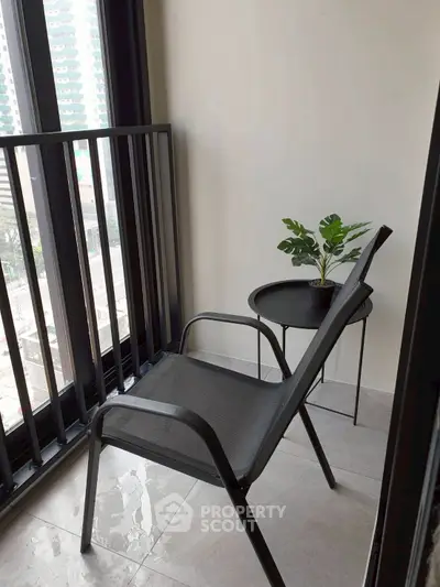 Cozy balcony with modern chair and small table, perfect for relaxation.