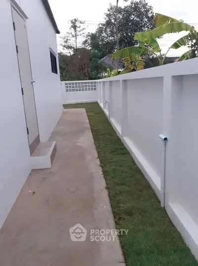 Modern side yard with white walls and fresh landscaping in a residential property.