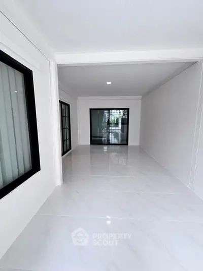 Spacious modern interior with sleek white tiles and large windows, perfect for versatile living space.
