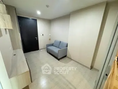 Modern apartment entrance with sleek wooden flooring and cozy seating area.