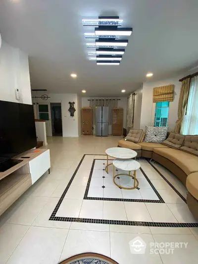 Spacious living room with modern decor and stylish lighting, featuring a large sectional sofa and sleek TV setup.