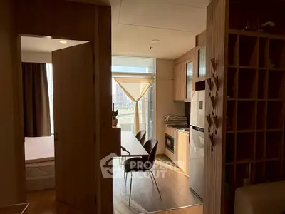 Modern apartment interior with open kitchen and dining area, featuring wooden cabinetry and natural light.