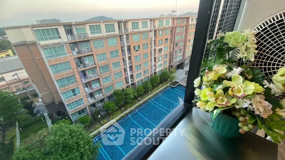 Stunning high-rise view with pool and lush greenery from a modern apartment window.