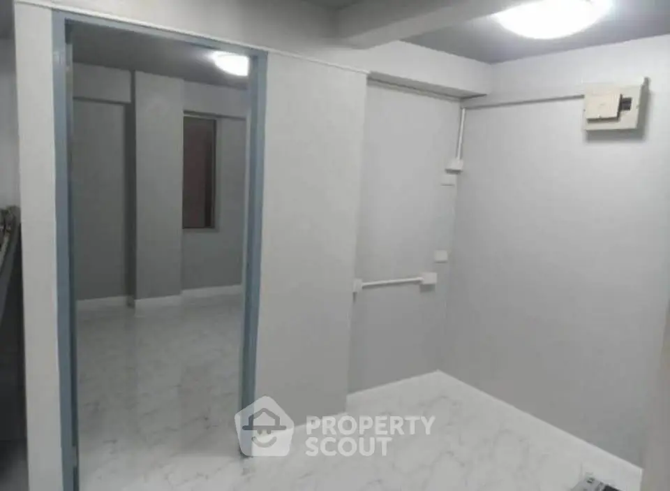 Minimalist interior space with white walls and tiled flooring, ideal for versatile use.