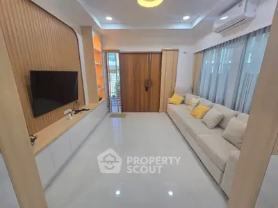 Modern living room with sleek design, featuring a cozy sofa, wall-mounted TV, and elegant lighting.