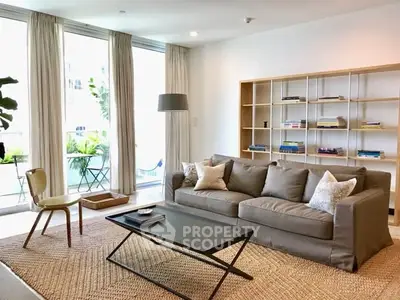 Modern living room with cozy sofa and stylish decor, featuring a large window with balcony view.
