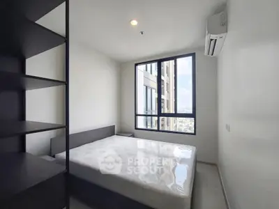 Modern bedroom with large window and city view in a high-rise apartment.