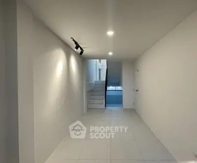 Spacious minimalist interior with sleek white tiles and modern lighting, perfect for versatile living space.