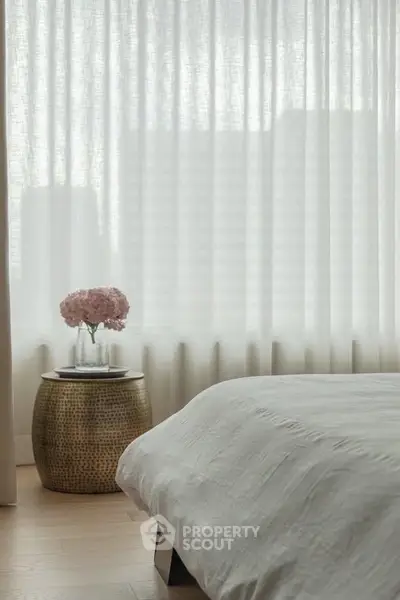 Elegant bedroom with soft lighting and chic decor, featuring a cozy bed and stylish side table with flowers.