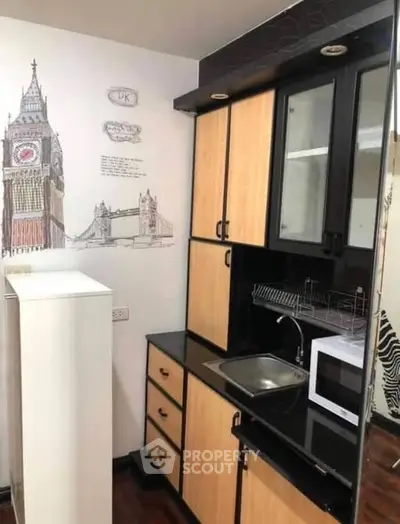 Charming compact kitchen with modern appliances and stylish cabinetry, featuring a unique London-themed wall art.