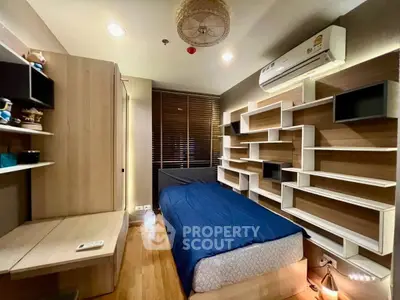 Modern bedroom with built-in shelves and air conditioning, featuring a cozy single bed and stylish lighting.