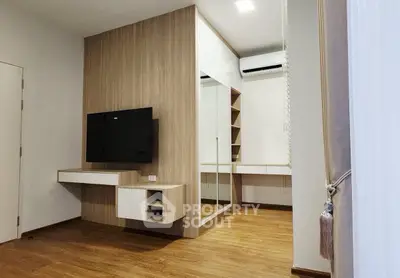 Modern living room with wooden flooring and wall-mounted TV, featuring sleek storage solutions.