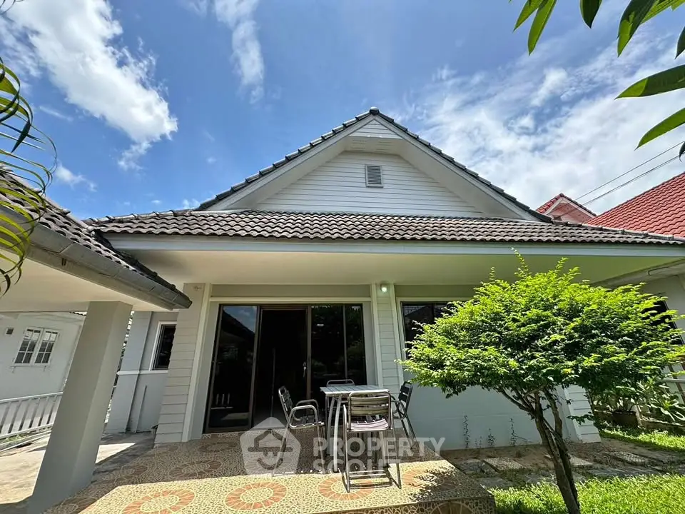 Charming single-story house with a spacious patio and lush greenery, perfect for outdoor relaxation.