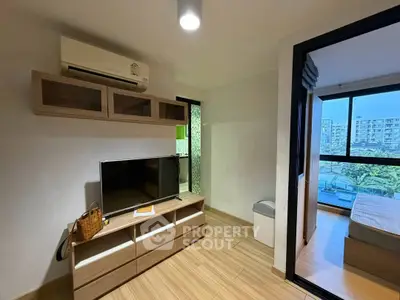 Modern apartment interior with TV unit and air conditioning, featuring a glimpse into a cozy bedroom with city view.