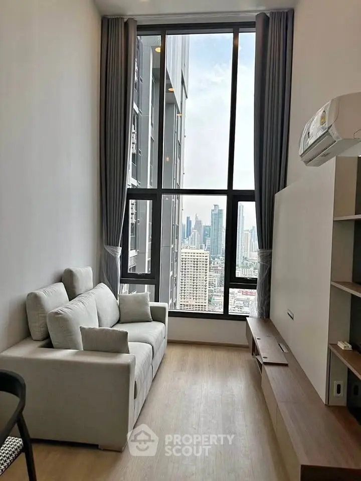 Modern living room with floor-to-ceiling windows and city view in high-rise apartment.
