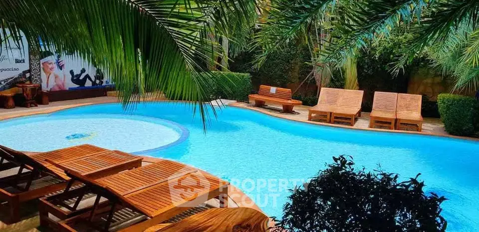 Luxurious outdoor pool area with wooden loungers and lush greenery, perfect for relaxation.