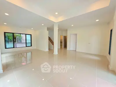 Spacious open-plan living room with glossy tiled floors and large windows.
