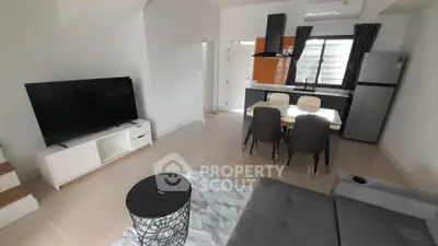 Modern open-plan living room with sleek kitchen, large TV, and stylish furniture.