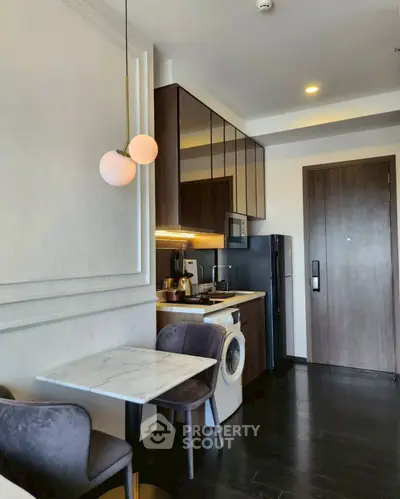 Modern kitchen with dining area, washing machine, and sleek cabinetry.