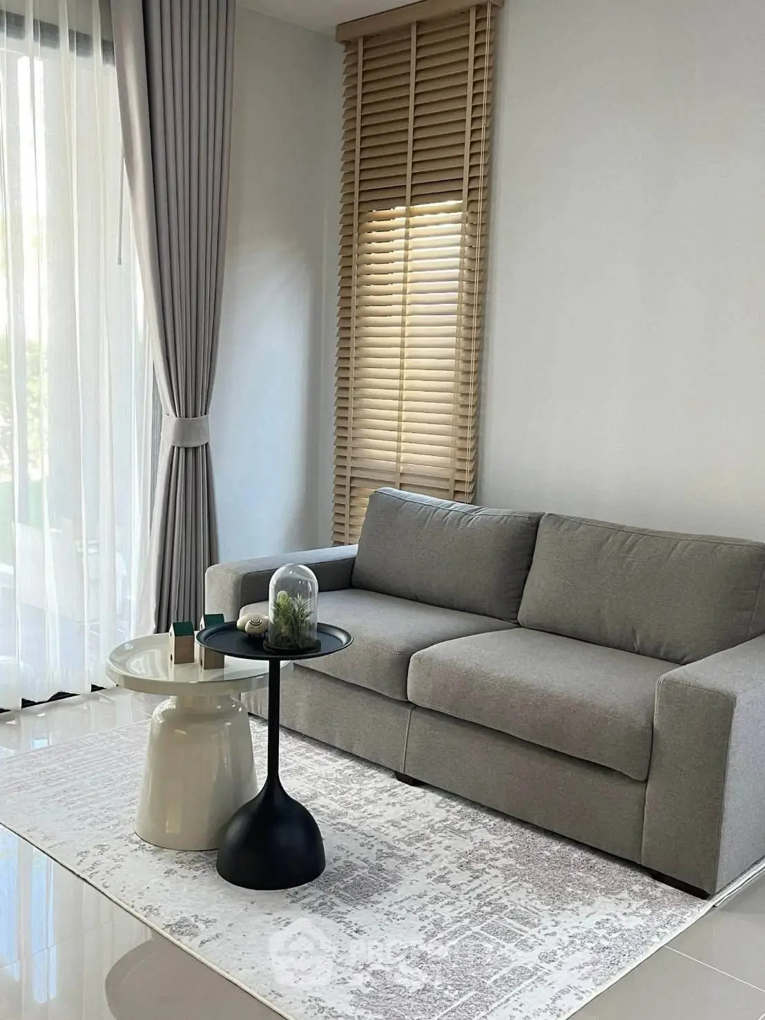 Modern living room with sleek gray sofa, stylish coffee table, and elegant floor-to-ceiling curtains.