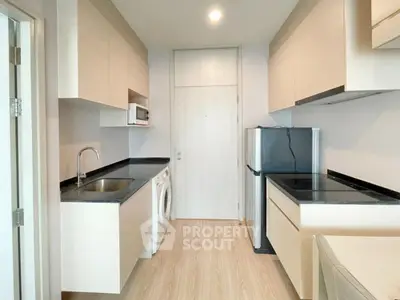 Modern kitchen with sleek cabinetry, washing machine, and microwave in a compact layout.