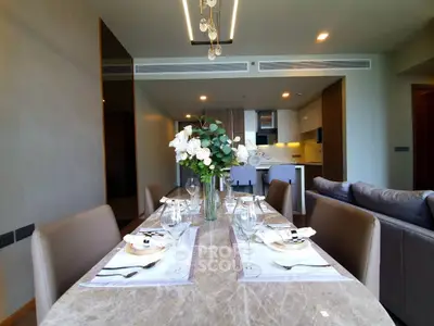 Luxurious dining area with elegant table setting and modern kitchen in open layout apartment.