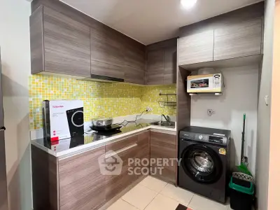 Modern kitchen with wooden cabinets, washing machine, and microwave in compact layout.