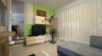 Modern living room with sleek furniture and vibrant green accent wall, featuring a cozy sofa and entertainment center.