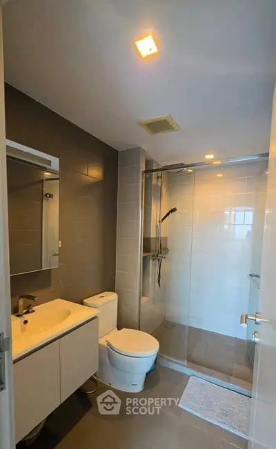 Modern bathroom with sleek design, featuring a glass-enclosed shower and contemporary fixtures.