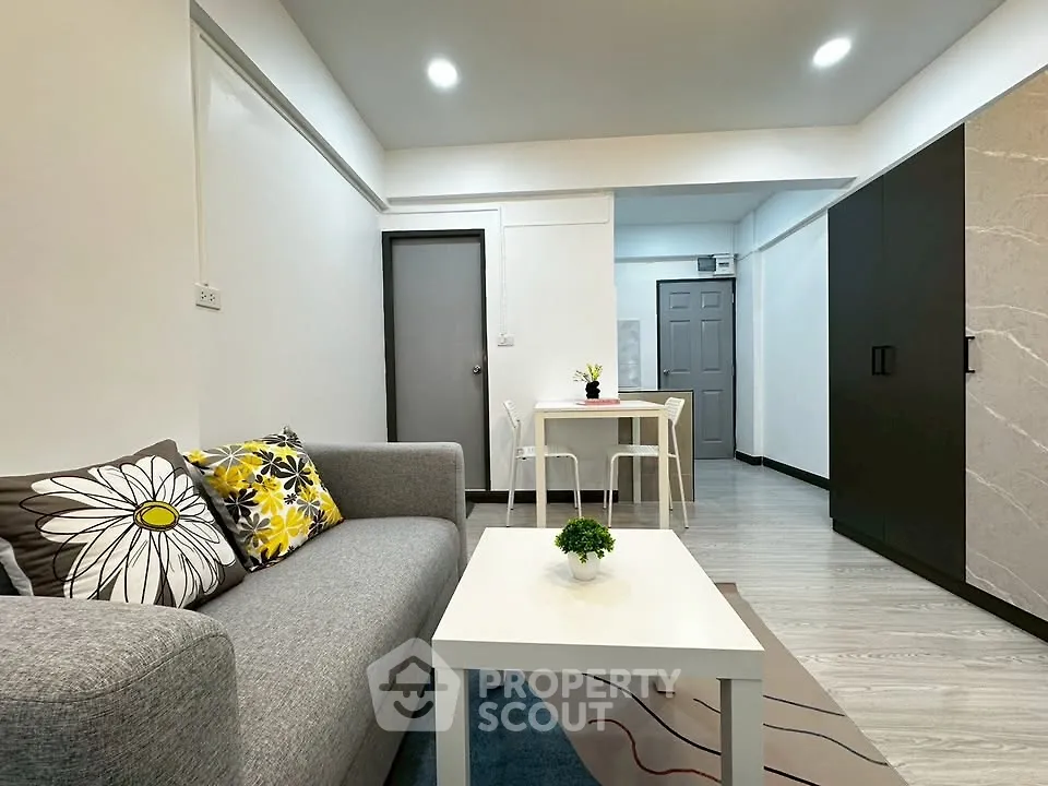 Modern living room with stylish gray sofa and dining area in open layout apartment.