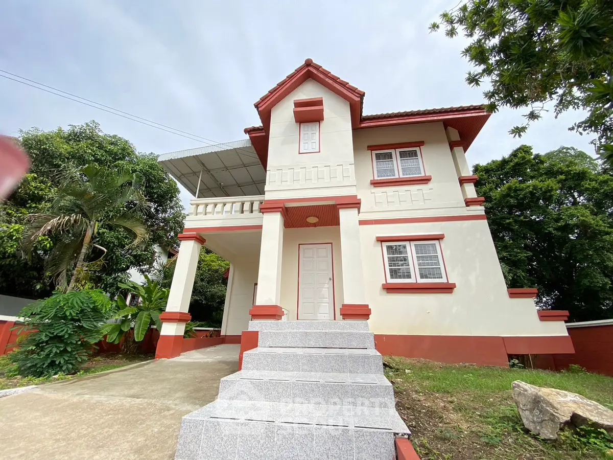 Charming two-story house with red accents and lush greenery