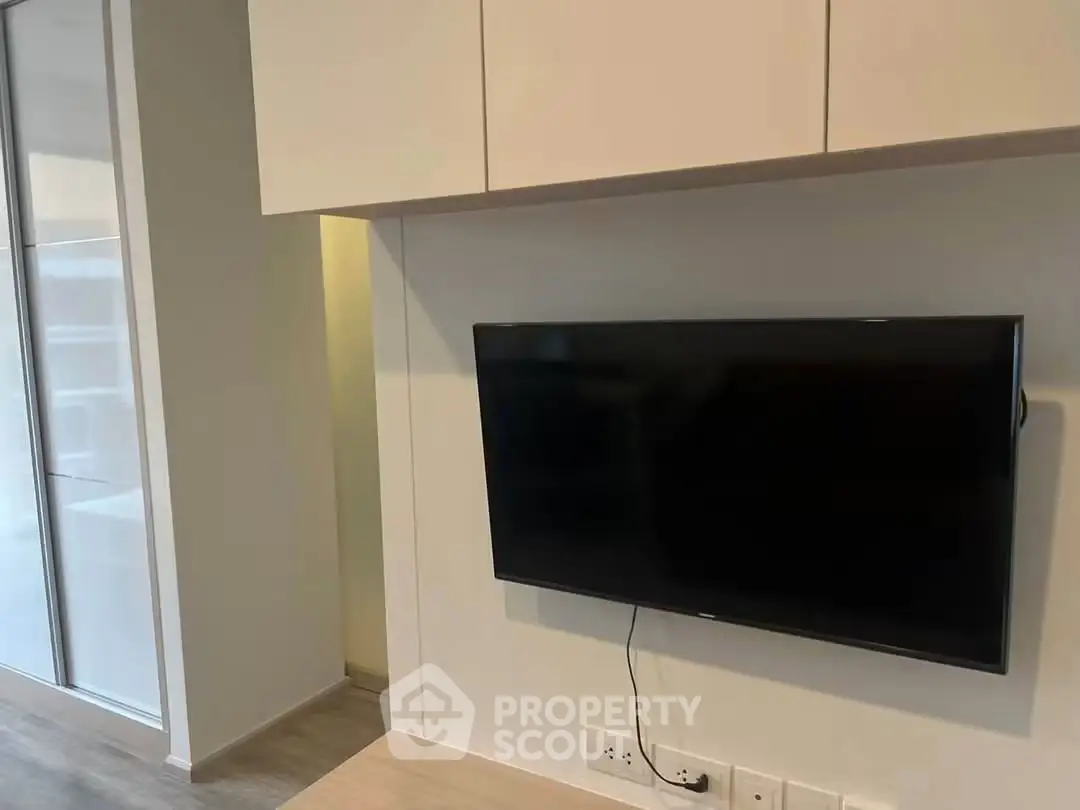 Modern living room with wall-mounted TV and sleek cabinetry in a stylish apartment.