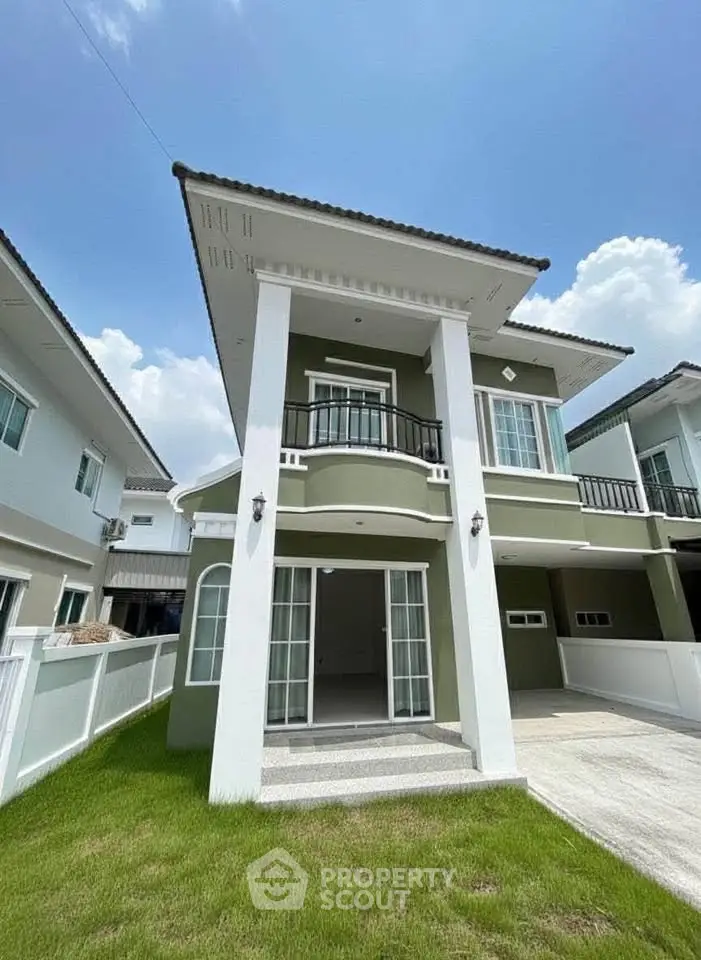 Modern two-story house with balcony and driveway in a sunny neighborhood.