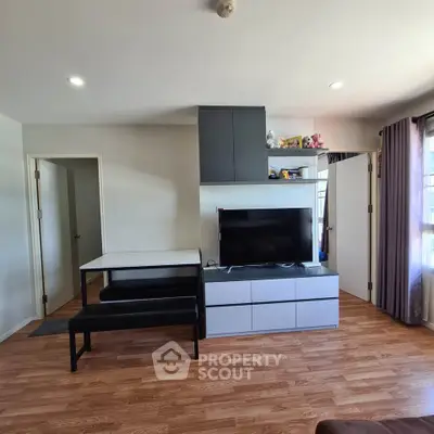 Modern living room with sleek TV unit and wooden flooring in a bright apartment.