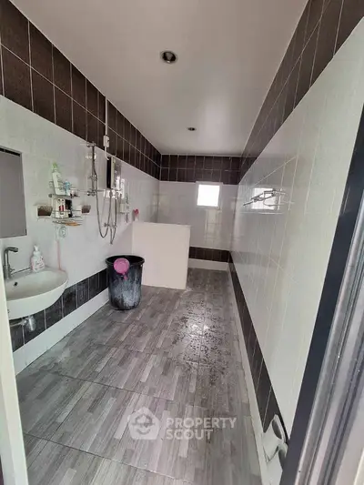 Spacious bathroom with modern tiles and shower area in a real estate property.