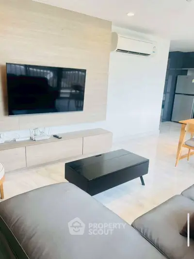 Modern living room with sleek furniture and wall-mounted TV in a stylish apartment.