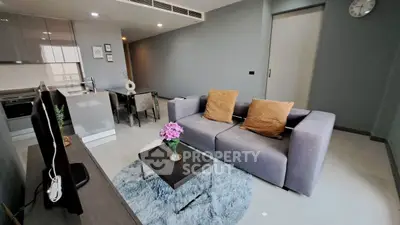 Modern living room with sleek kitchen, cozy sofa, and stylish decor in open-concept apartment.