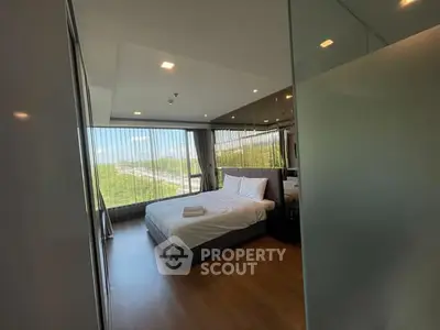 Modern bedroom with large windows offering scenic views and natural light.