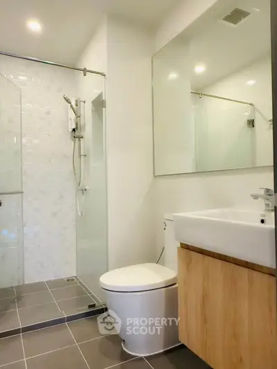 Modern bathroom with glass shower and sleek fixtures in contemporary apartment.