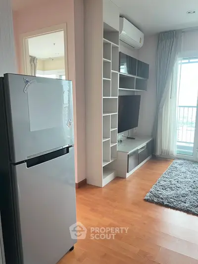 Modern living room with sleek TV unit and balcony view, featuring a stylish fridge and wooden flooring.