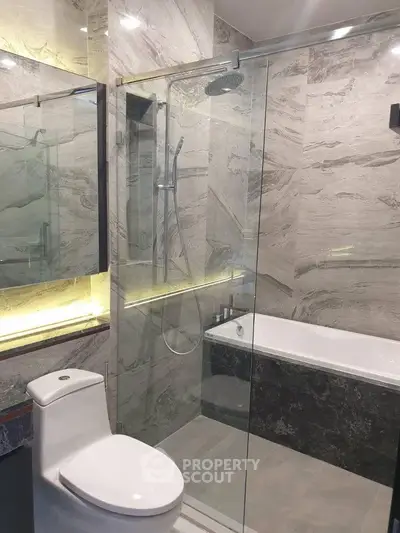 Luxurious modern bathroom with glass shower and elegant marble finishes.