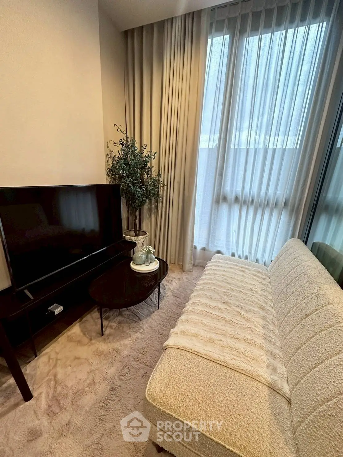 Cozy living room with plush sofa, TV, and elegant curtains