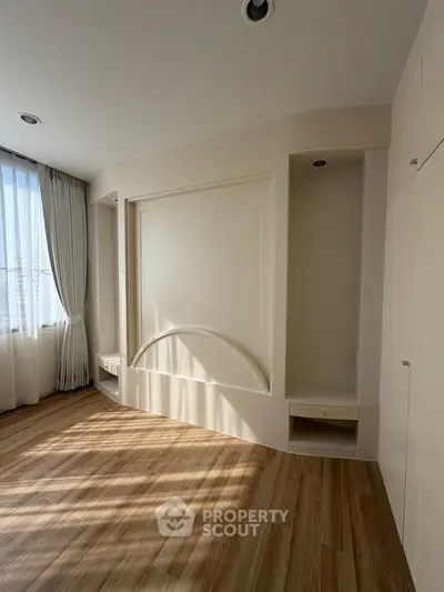 Spacious empty room with elegant wood flooring and natural light, perfect for customization.