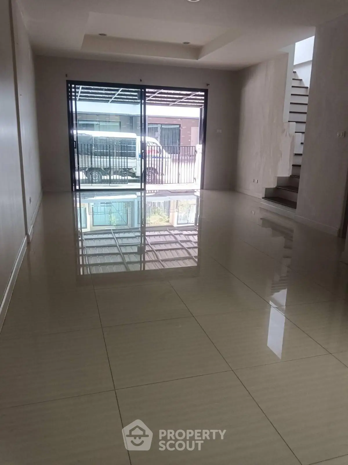 Spacious empty living room with glossy tiled floors and large window