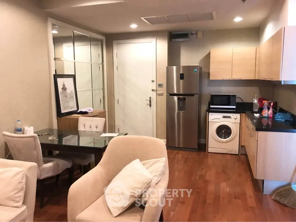 Modern apartment interior with open kitchen and cozy living area featuring wooden flooring and stylish furniture.