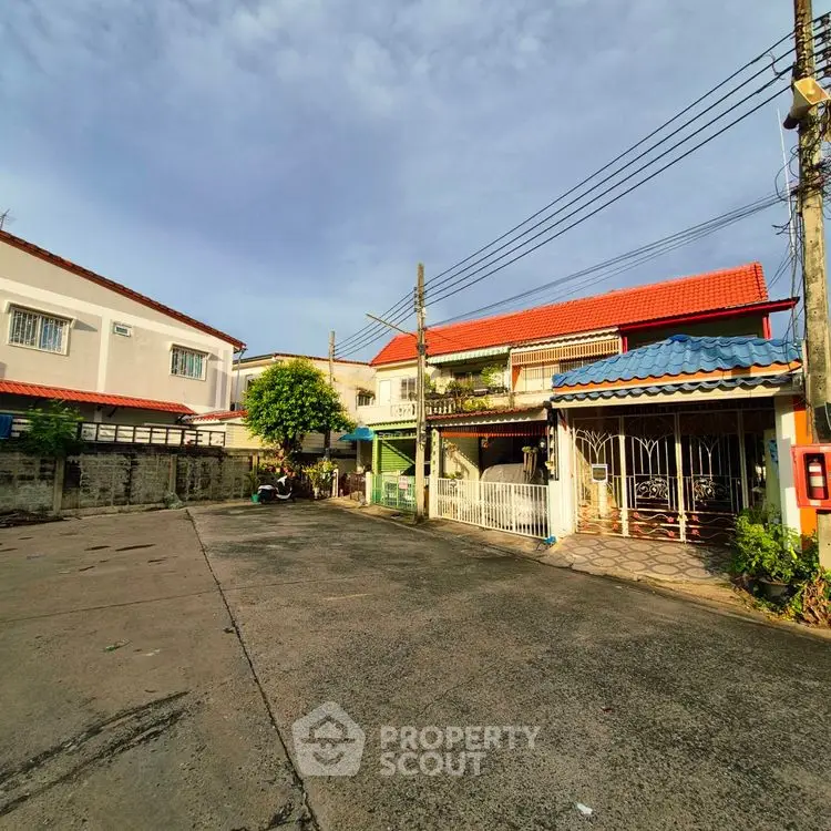 Charming residential street with traditional houses and vibrant red roofs under a clear sky.