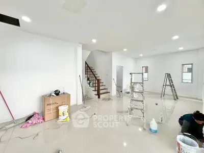 Spacious modern living room under renovation with sleek staircase and glossy tile flooring.