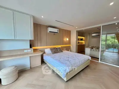 Spacious modern bedroom with stylish decor and adjacent living area, featuring elegant wood flooring and ambient lighting.